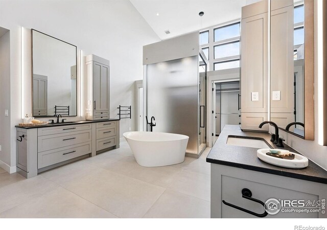 1563 Spring Creek Xing, Lafayette, CO 80026 - full bathroom with high vaulted ceiling, two vanities, a freestanding bath, and tile patterned floors