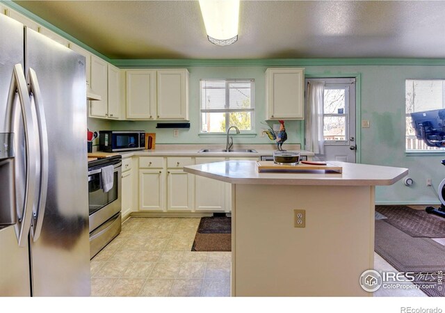 5241 E 128th Way, Thornton, CO 80241 - kitchen featuring appliances with stainless steel finishes, a sink, light countertops, a center island, and healthy amount of natural light