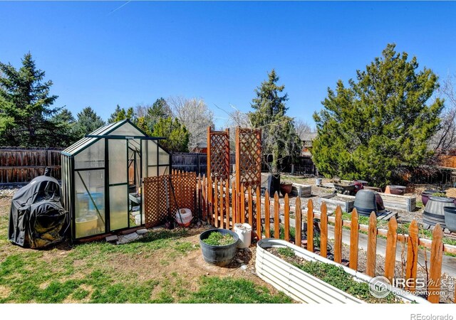 5241 E 128th Way, Thornton, CO 80241 - fenced backyard featuring a greenhouse, a vegetable garden, and an outbuilding