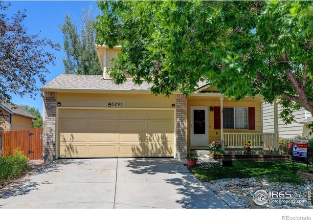 5241 E 128th Way, Thornton, CO 80241 - view of property hidden behind natural elements featuring concrete driveway, covered porch, an attached garage, and brick siding