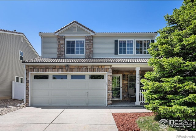 18656 Kelly Pl, Denver, CO 80249 - traditional-style house with stone siding, concrete driveway, covered porch, and a tiled roof
