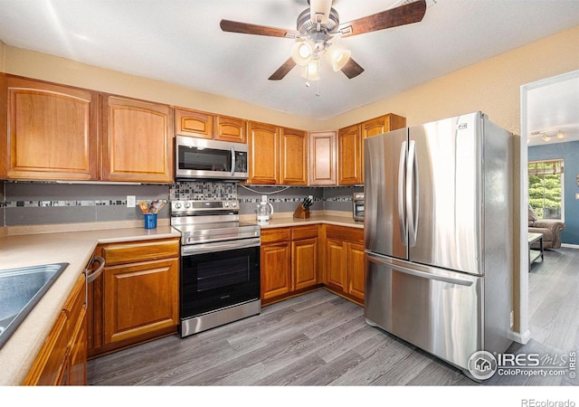 18656 Kelly Pl, Denver, CO 80249 - kitchen with appliances with stainless steel finishes, light wood-type flooring, light countertops, a sink, and backsplash