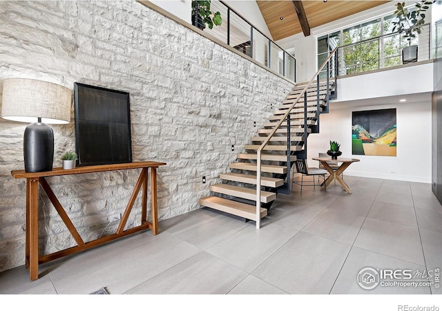 2100 Kohler Dr, Boulder, CO 80305 - stairway featuring high vaulted ceiling, wood ceiling with exposed beams, tile patterned floors, and baseboards