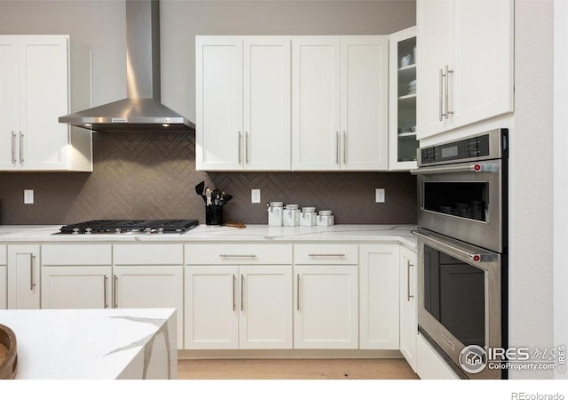 730 Promenade Dr, Superior, CO 80027 - kitchen featuring wall chimney range hood, appliances with stainless steel finishes, white cabinets, and decorative backsplash