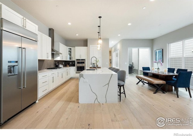 730 Promenade Dr, Superior, CO 80027 - kitchen with appliances with stainless steel finishes, wall chimney range hood, a sink, light wood-style floors, and recessed lighting