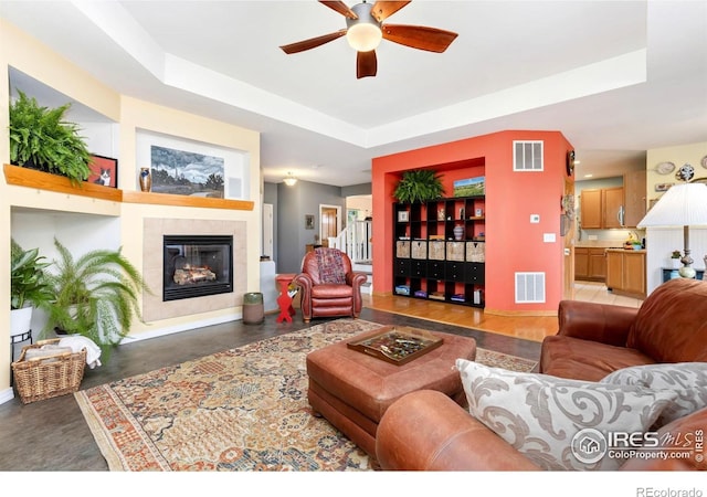 633 Deerwood Dr, Longmont, CO 80504 - living room with a ceiling fan, a tiled fireplace, and a tray ceiling