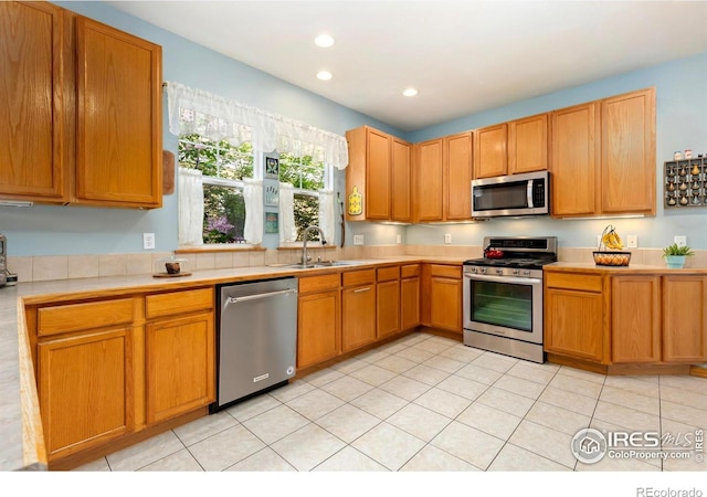633 Deerwood Dr, Longmont, CO 80504 - kitchen with stainless steel appliances, light countertops, recessed lighting, light tile patterned floors, and brown cabinets