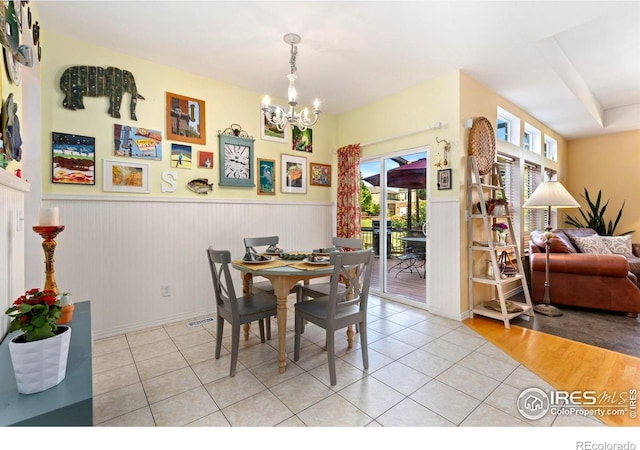 633 Deerwood Dr, Longmont, CO 80504 - dining space with a chandelier, tile patterned flooring, healthy amount of natural light, and a wainscoted wall