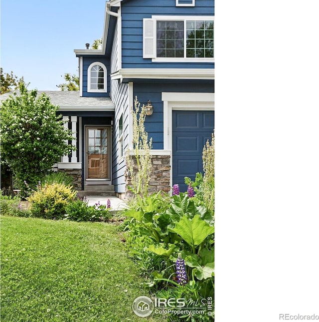 823 Timothy Dr, Longmont, CO 80503 - doorway to property featuring a lawn, an attached garage, and stone siding