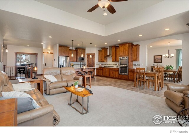 5532 Maidenhead Dr, Windsor, CO 80550 - living room with arched walkways, a chandelier, a ceiling fan, light wood-type flooring, and recessed lighting