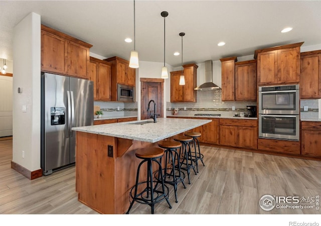 5532 Maidenhead Dr, Windsor, CO 80550 - kitchen with appliances with stainless steel finishes, wall chimney range hood, a sink, brown cabinetry, and light wood-style floors