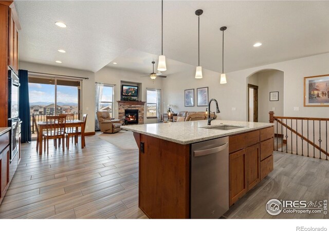 5532 Maidenhead Dr, Windsor, CO 80550 - kitchen with stainless steel dishwasher, a sink, ceiling fan, a stone fireplace, and arched walkways