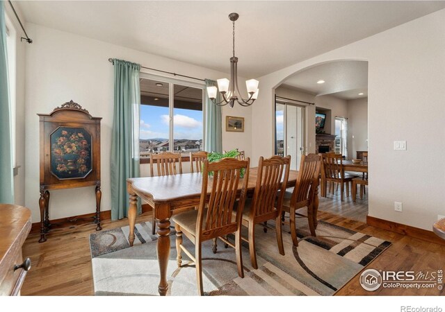5532 Maidenhead Dr, Windsor, CO 80550 - dining room with arched walkways, light wood-style flooring, a chandelier, and baseboards
