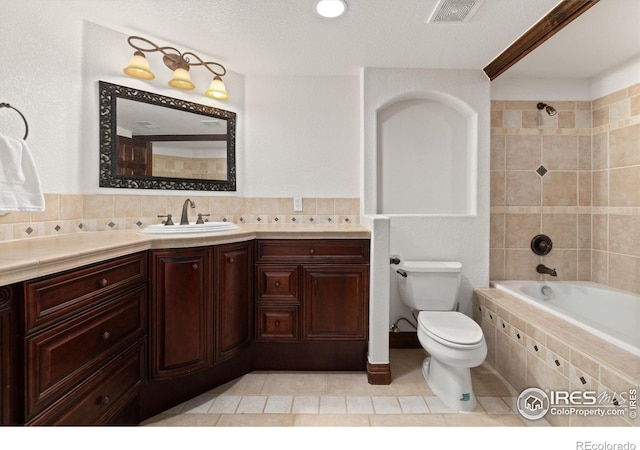 2549 Cowley Dr, Lafayette, CO 80026 - bathroom featuring toilet, vanity, tiled shower / bath combo, tile patterned floors, and backsplash