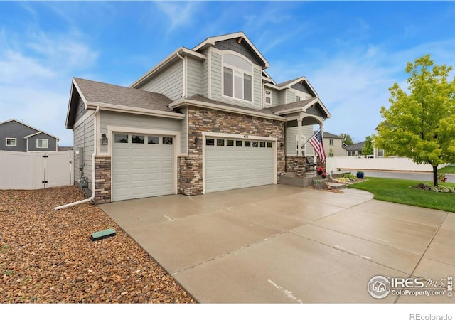 426 Gannet Peak Dr, Windsor, CO 80550 - view of front of home featuring driveway, a gate, stone siding, and a garage