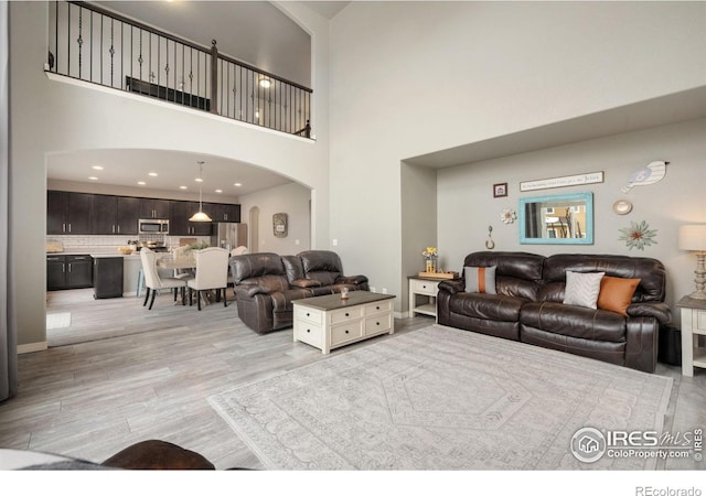 426 Gannet Peak Dr, Windsor, CO 80550 - living room with arched walkways, light wood finished floors, a high ceiling, and recessed lighting