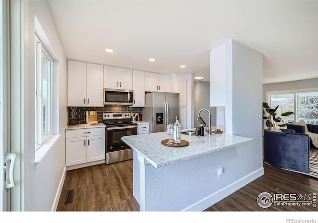 1714 Zeus Dr, Lafayette, CO 80026 - kitchen with appliances with stainless steel finishes, dark wood finished floors, baseboards, white cabinets, and recessed lighting