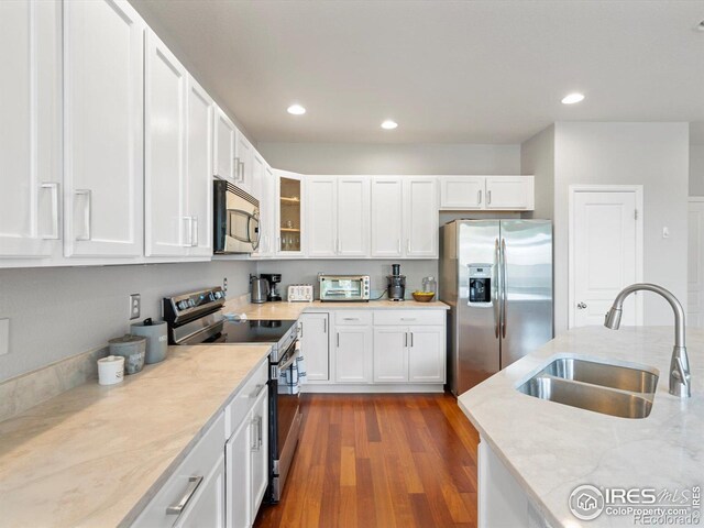 4795 Raven Run, Broomfield, CO 80023 - kitchen with appliances with stainless steel finishes, a sink, white cabinets, dark wood-type flooring, and glass insert cabinets