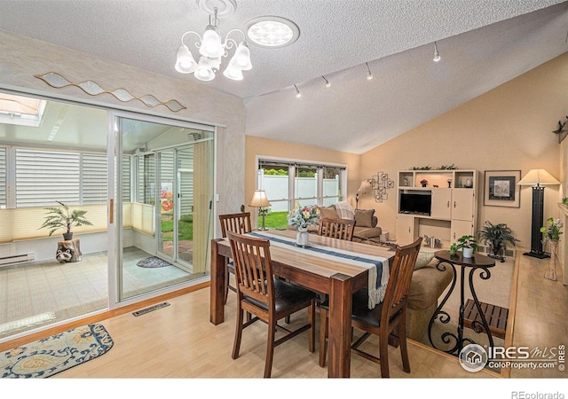 2409 Flora Dr, Loveland, CO 80537 - dining space with a textured ceiling, lofted ceiling, wood finished floors, a chandelier, and baseboard heating