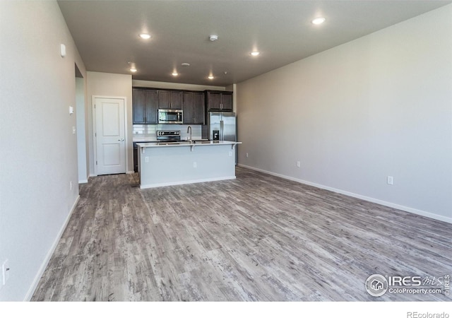 1811 Bounty Dr Unit 4, Windsor, CO 80550 - kitchen with appliances with stainless steel finishes, open floor plan, light wood-type flooring, an island with sink, and baseboards