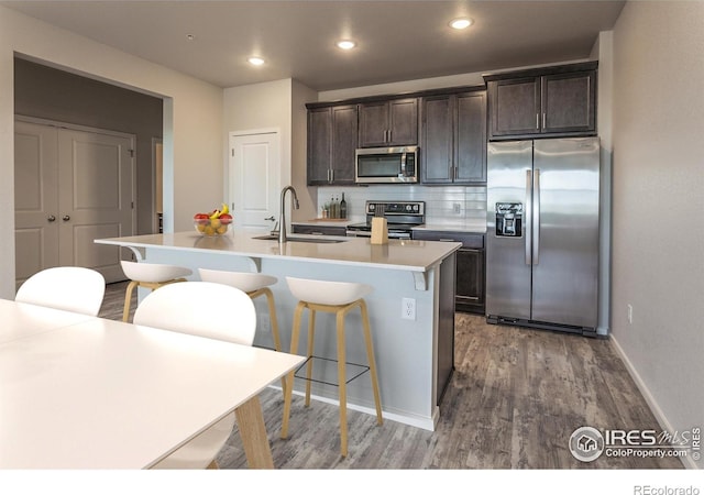 1811 Bounty Dr Unit 4, Windsor, CO 80550 - kitchen featuring stainless steel appliances, a sink, wood finished floors, dark brown cabinets, and a center island with sink