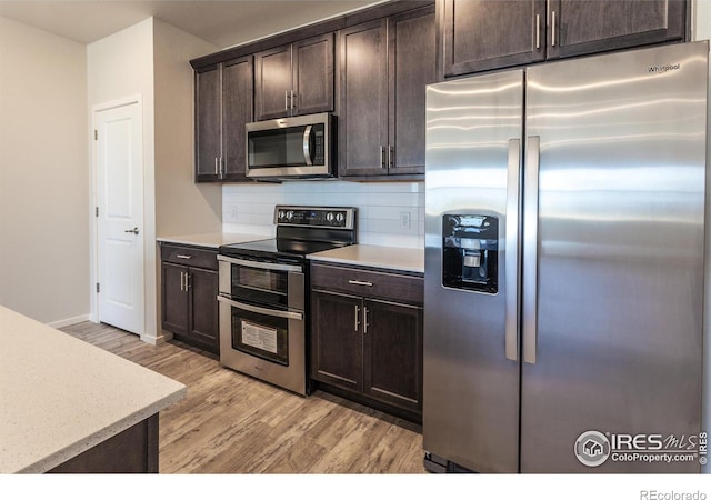 1811 Bounty Dr Unit 4, Windsor, CO 80550 - kitchen featuring appliances with stainless steel finishes, light wood-style flooring, decorative backsplash, dark brown cabinetry, and baseboards