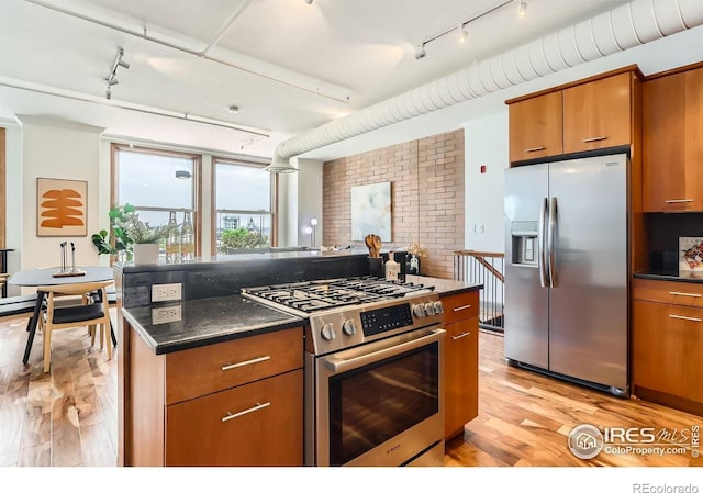 2245 Blake St Unit D, Denver, CO 80205 - kitchen with appliances with stainless steel finishes, rail lighting, light wood finished floors, brown cabinetry, and a kitchen island