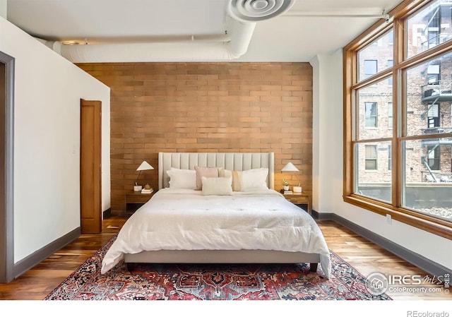 2245 Blake St Unit D, Denver, CO 80205 - bedroom featuring brick wall and wood finished floors