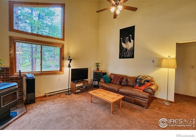 38 Navajo Trl, Nederland, CO 80466 - living area featuring a wood stove, carpet floors, a high ceiling, ceiling fan, and a baseboard radiator