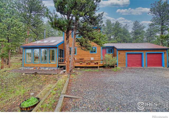 38 Navajo Trl, Nederland, CO 80466 - view of front of home with a garage, a sunroom, gravel driveway, and a wooden deck
