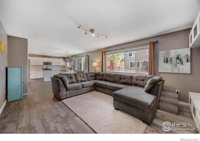 5822 Shenandoah Ave, Firestone, CO 80504 - living area with light wood finished floors, baseboards, recessed lighting, a chandelier, and rail lighting