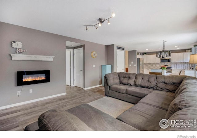 5822 Shenandoah Ave, Firestone, CO 80504 - living room featuring a chandelier, light wood finished floors, baseboards, a glass covered fireplace, and recessed lighting