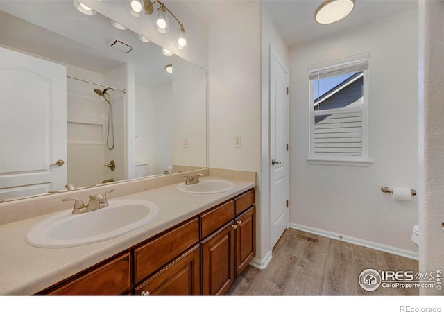 5822 Shenandoah Ave, Firestone, CO 80504 - full bathroom featuring toilet, wood finished floors, double vanity, a shower, and baseboards