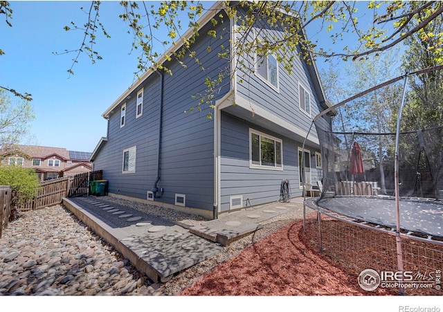 5822 Shenandoah Ave, Firestone, CO 80504 - back of house with a trampoline and a fenced backyard