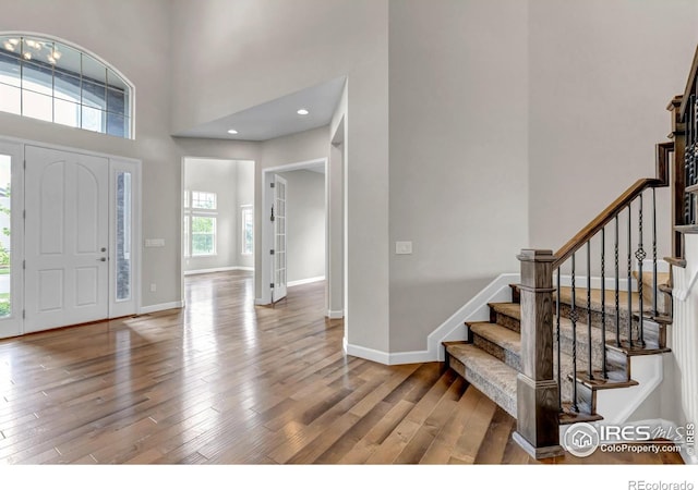 913 Green Mountain Dr, Erie, CO 80516 - foyer featuring wood finished floors, stairway, a towering ceiling, and baseboards