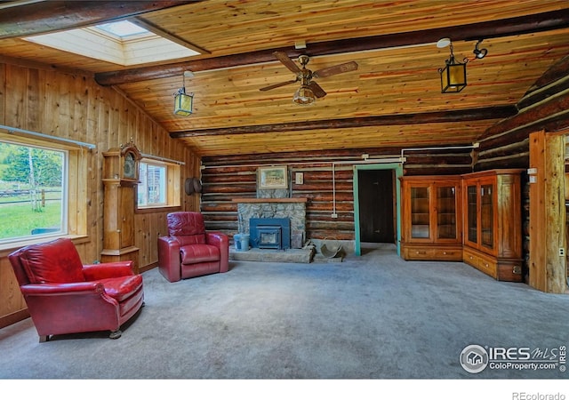 545 Eldorado Ave, Nederland, CO 80466 - carpeted living room featuring wood ceiling, a skylight, rustic walls, ceiling fan, and a stone fireplace
