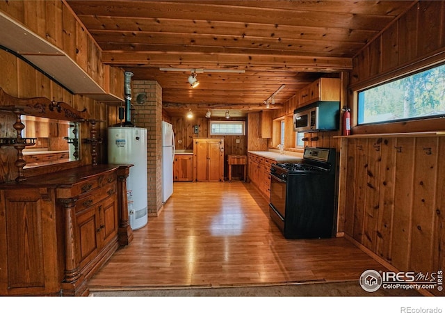 545 Eldorado Ave, Nederland, CO 80466 - kitchen featuring black range with gas cooktop, gas water heater, freestanding refrigerator, light wood-style floors, and wooden walls
