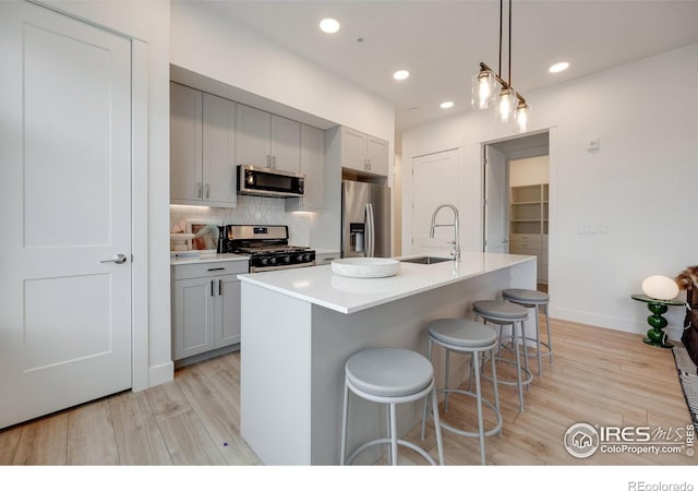 2876 W 53rd Ave Unit 301, Denver, CO 80221 - kitchen featuring appliances with stainless steel finishes, gray cabinets, a sink, light wood-type flooring, and tasteful backsplash