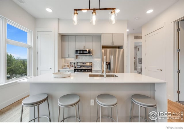 2876 W 53rd Ave Unit 301, Denver, CO 80221 - kitchen featuring appliances with stainless steel finishes, gray cabinets, backsplash, light wood-style flooring, and recessed lighting