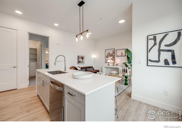 2876 W 53rd Ave Unit 301, Denver, CO 80221 - kitchen featuring a sink, light wood-type flooring, light countertops, pendant lighting, and an island with sink