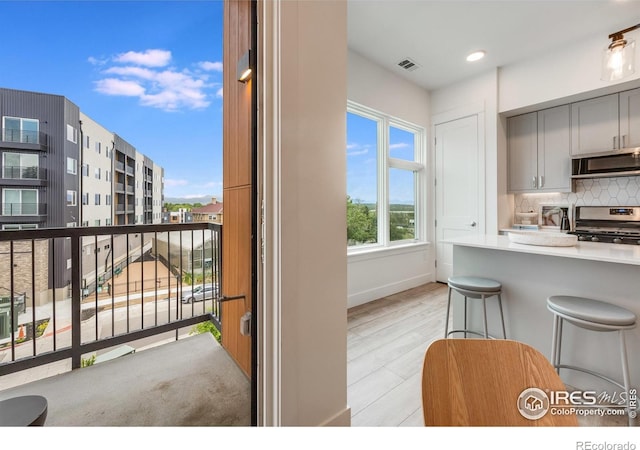 2876 W 53rd Ave Unit 301, Denver, CO 80221 - kitchen featuring appliances with stainless steel finishes, backsplash, baseboards, a kitchen bar, and light countertops