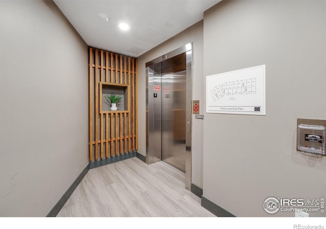 2876 W 53rd Ave Unit 301, Denver, CO 80221 - hallway with elevator, wood finished floors, and baseboards