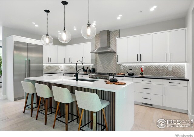 2860 Table Mesa Dr, Boulder, CO 80305 - kitchen with wall chimney range hood, stainless steel built in refrigerator, decorative backsplash, light wood finished floors, and recessed lighting