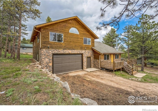 24192 W County Road 74e, Red Feather Lakes, CO 80545 - rustic home with stone siding, driveway, a deck, and an attached garage