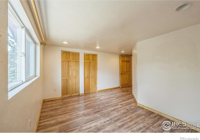 24192 W County Road 74e, Red Feather Lakes, CO 80545 - unfurnished bedroom featuring two closets, light wood-type flooring, recessed lighting, multiple windows, and baseboards