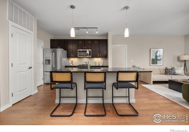 13598 Via Varra Unit 404, Broomfield, CO 80020 - kitchen with appliances with stainless steel finishes, dark countertops, a kitchen breakfast bar, and light wood finished floors