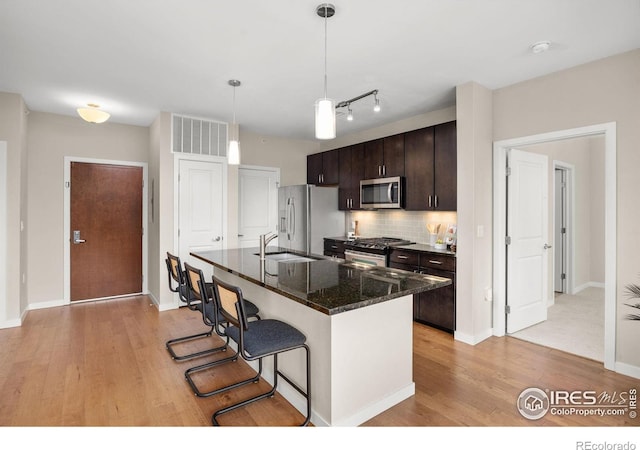 13598 Via Varra Unit 404, Broomfield, CO 80020 - kitchen with stainless steel appliances, a sink, light wood-style floors, and a breakfast bar