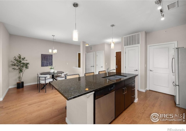 13598 Via Varra Unit 404, Broomfield, CO 80020 - kitchen with stainless steel appliances, a sink, light wood-style flooring, and a kitchen island with sink