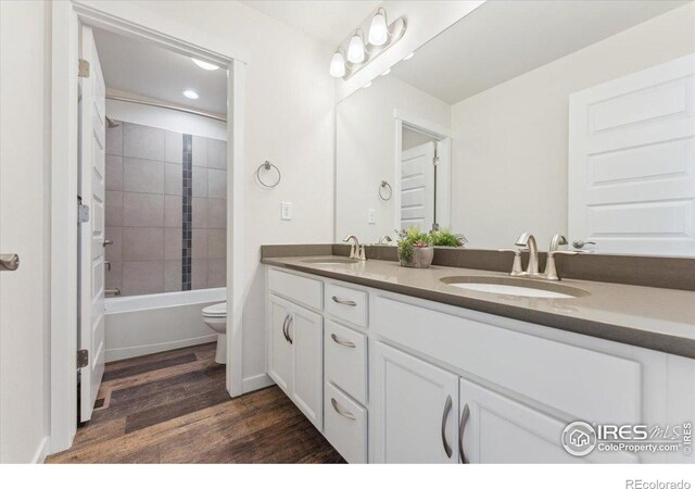 1257 Wild Basin Rd, Severance, CO 80550 - full bath with double vanity, toilet, wood finished floors, and bathtub / shower combination