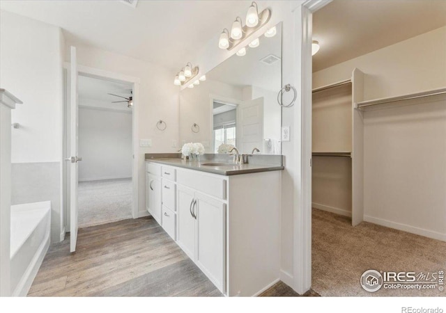 1257 Wild Basin Rd, Severance, CO 80550 - full bath with ceiling fan, double vanity, a bathtub, a spacious closet, and baseboards